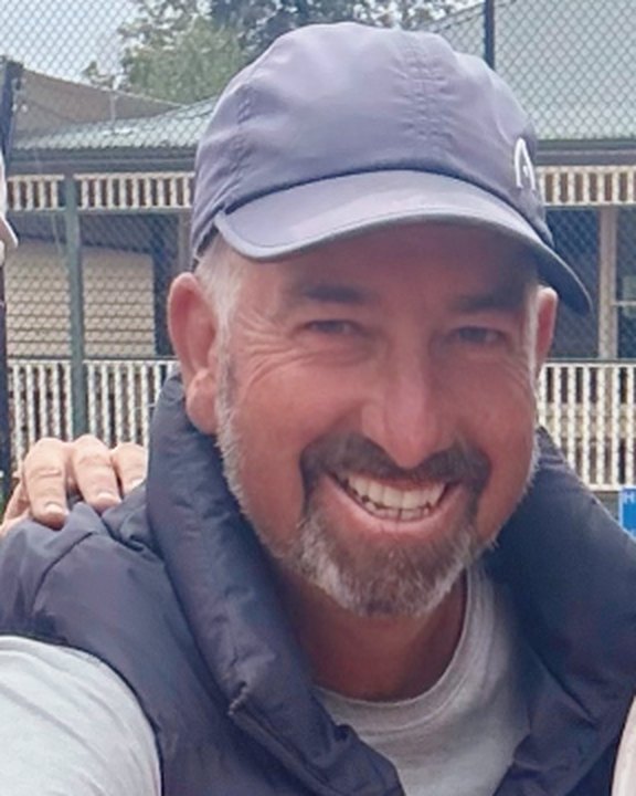Coach Dieter Ackermann smiling on court at East Camberwell Tennis Club